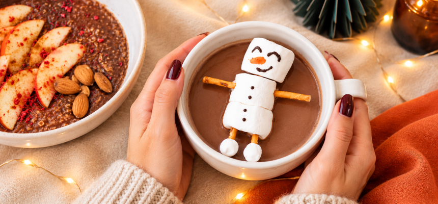 Frauenhände halten eine Tasse Kakao mit einem Marshmallow-Schneemann